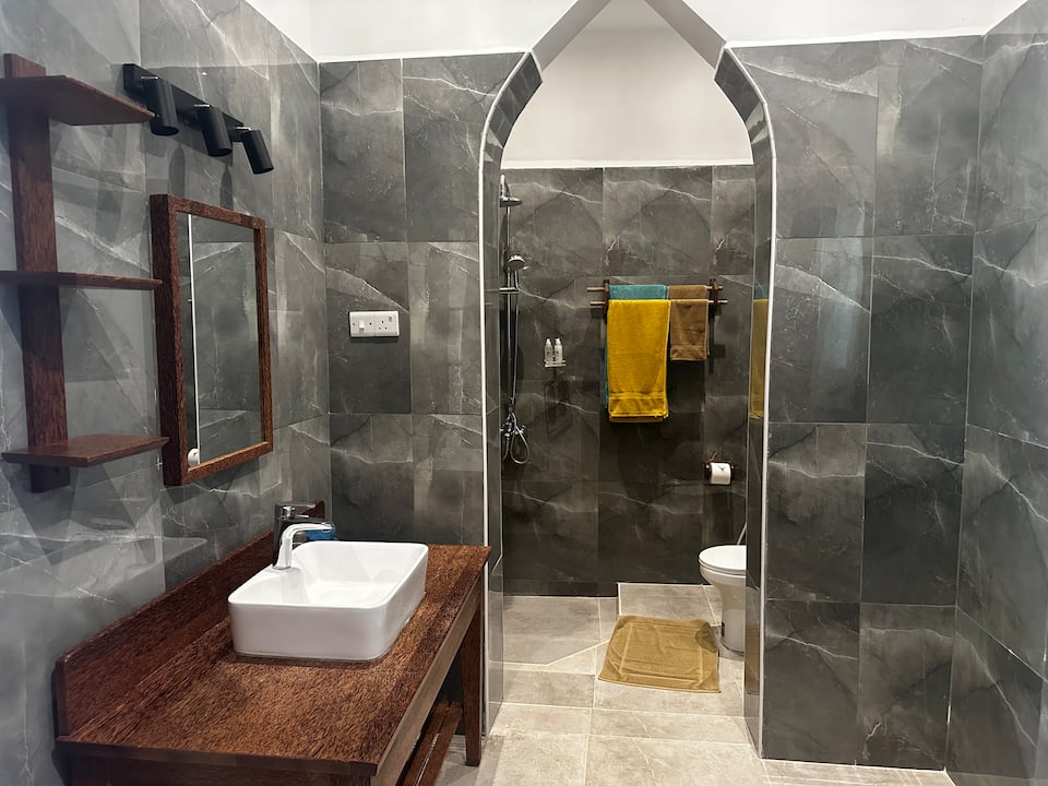 En-suite bathroom with pointed archway, dark marble tiles and wooden vanity